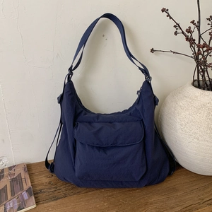 Detail einer dunkelblauen Nylon-Umhängetasche mit Vordertasche auf einer Holzfläche