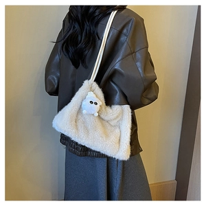 Dettaglio borsa a secchiello in peluche beige con ciondolo mostro e tracolla lunga