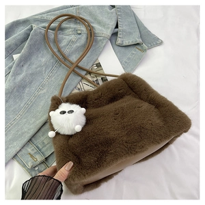 Dettaglio della borsa a secchiello in peluche marrone con tracolla in pelle e ciondolo