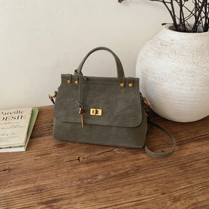 Vintage olive green handbag with gold lock and adjustable strap on a rustic wood surface
