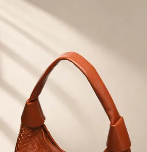 Détail de la texture tressée et de l'anse ronde confortable d'un grand sac en cuir marron