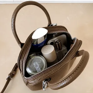 Macro shot showing internal capacity of brown leather shell bag with daily essentials