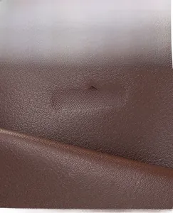 Macro shot of dark brown pebbled leather texture with embossed brand logo on the bag