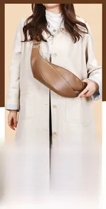 Close-up of brown leather crescent bag showing layered pleats and metal buckle detail