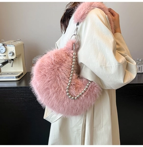 Detailed view of pink plush crescent bag with silver beaded chain worn on a beige coat