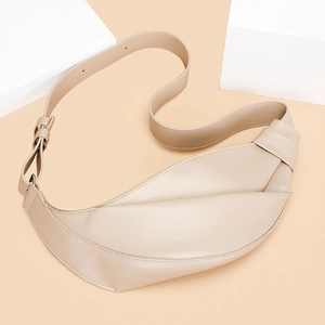 Detail view of beige crescent bag featuring unique side knot and adjustable shoulder strap