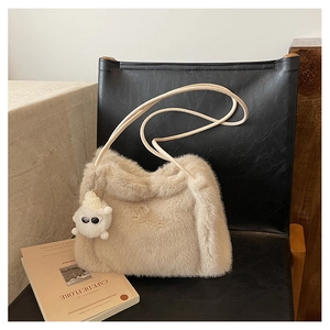 Dettaglio della borsa a secchiello in finta pelliccia beige con ciondolo in peluche