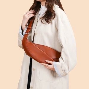 Detailed texture of caramel brown synthetic leather crescent bag with adjustable strap
