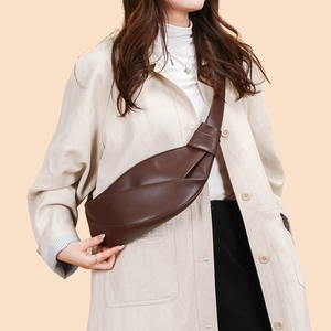 Detail view of dark brown croissant crossbody bag with knot shoulder strap design