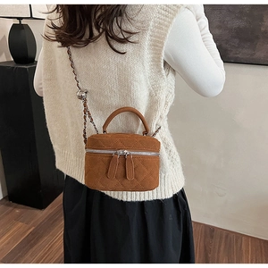 Detail of caramel suede quilted mini bag with silver chain strap and top handle