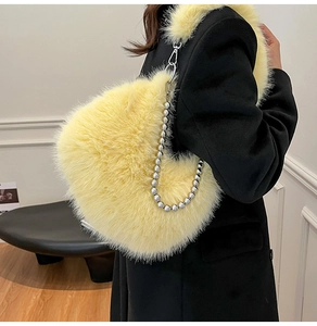 Detail of a bright yellow heart-shaped plush bag featuring a silver beaded metal chain strap