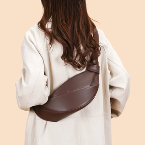 Detailed back view of a dark brown croissant crossbody bag worn with a white trench coat