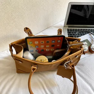Macro view of brown tote bag interior showing capacity for tablet, phone, and daily essentials