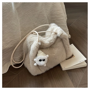 Dettaglio macro della borsa a secchiello in ecopelliccia beige con ciondolo e tracolle