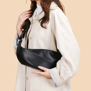 Side view of a black crescent crossbody bag worn with a stylish beige trench coat