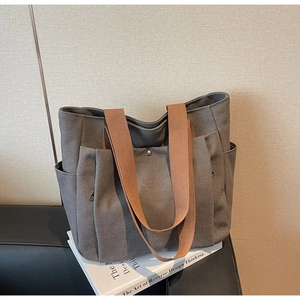 Detail view of dark grey canvas tote bag showing metal snap closure and woven strap