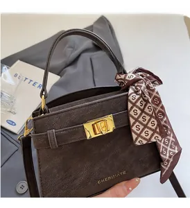 Vue détaillée du sac à main en daim marron foncé avec fermoir doré et foulard en soie