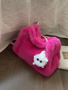 Secchiello chic in ecopelliccia rosa shocking con ciondolo mostro su pavimento in legno