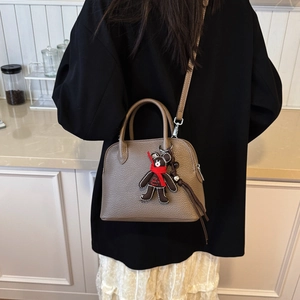 Brown litchi grain shell bag with cute bear charm shown in a lifestyle setting