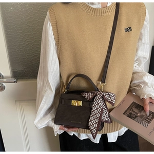 Détail d'un sac à main marron foncé avec fermoir doré et élégant foulard en soie à motifs