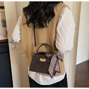 Détail d'un sac à main vintage marron foncé avec boucle en métal et foulard en soie