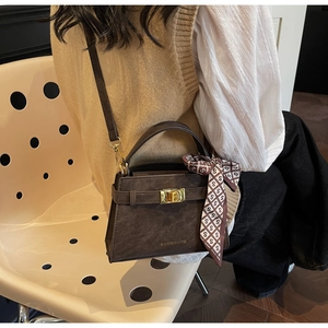 Détail du sac à main en cuir marron foncé avec fermoir doré et poignée en foulard de soie