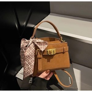 Détail d'un sac à main en daim marron foncé avec fermoir doré et foulard décoratif en soie