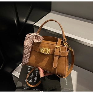 Détail du sac bandoulière marron avec fermoir métallique et foulard en soie au manche