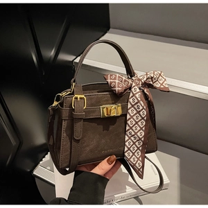Détail du sac à main en cuir marron avec fermoir doré et foulard en soie décoratif