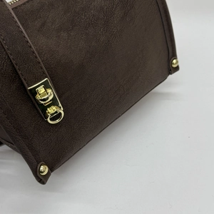 Detail of dark brown pebble leather texture and polished gold hardware on a shoulder bag