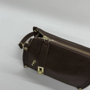 Close-up of retro brown leather shoulder bag with gold zipper and pebble grain texture