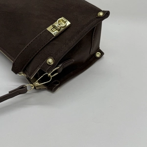 Detail of dark brown retro shoulder bag with golden twist lock and metal rivets hardware