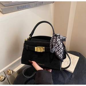 Détail d'un sac à main noir en daim avec fermoir doré et foulard en soie géométrique