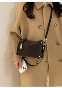 Detail of dark brown crossbody bag with gold hardware worn on an autumn wool coat