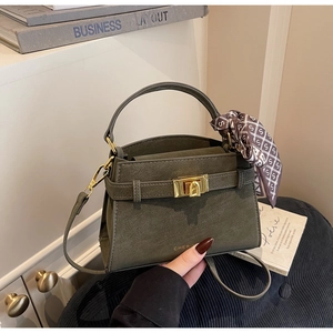 Gros plan du sac bandoulière vert olive avec fermoir doré et foulard en soie à carreaux