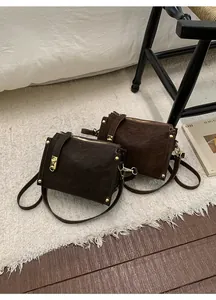 Detail of retro coffee brown crossbody bags with gold rivets and vintage texture