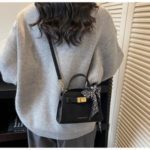 Détail du sac à main en cuir noir avec foulard en soie et fermoir doré sur un mannequin