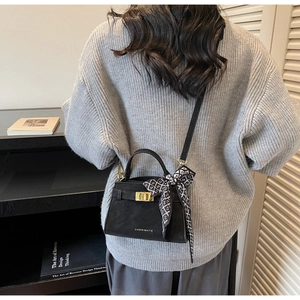 Détails d'un sac à main en cuir noir avec foulard en soie et finitions métalliques dorées