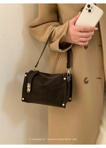 Detail of dark brown retro shoulder bag with gold studs on camel cashmere coat