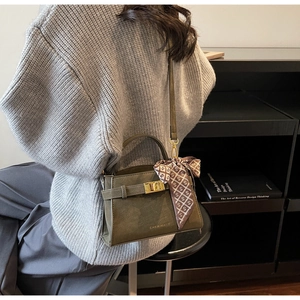 Détail du sac à main en cuir vert olive avec ferrures dorées et foulard décoratif