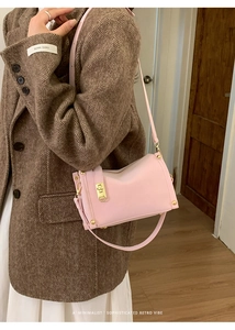 Pink retro square shoulder bag with gold hardware worn by a model in a brown blazer