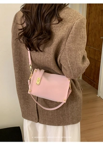 Detailed view of the pink retro shoulder bag with gold rivets on a model's wool coat