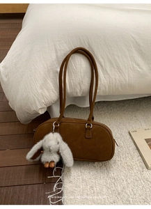 Detalle del bolso de hombro marrón retro con colgante de conejo en un ambiente minimalista