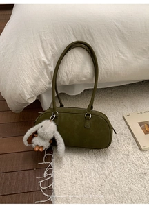 Detalle de bolso de hombro en gamuza verde oscuro con colgante de conejo de peluche