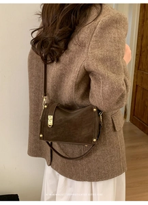 Close-up of retro brown leather crossbody bag with vintage gold hardware and rivets