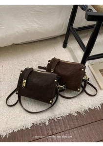Close-up of retro brown suede crossbody bags with gold hardware on white rug