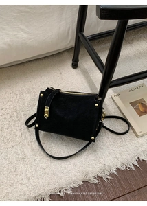 Detailed macro view of a vintage black suede handbag with gold zipper and metal rivets