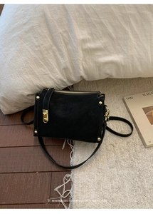 Detail view of retro black suede shoulder bag with gold metal lock and studs