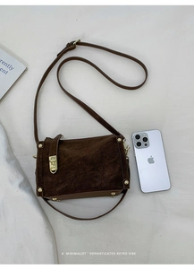 Detailed top view of brown suede crossbody bag with gold studs and a sleek metal lock