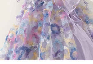 Close-up of girls purple tulle dress with colorful 3D floral petals and mesh texture